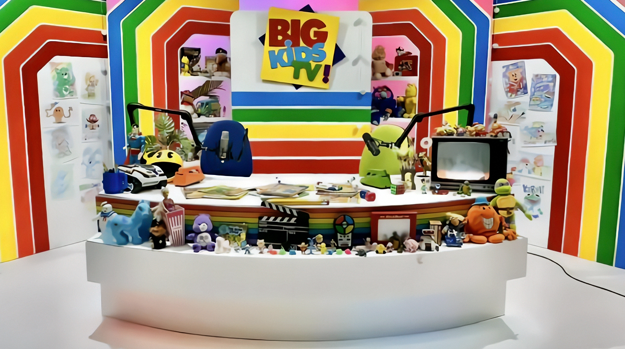 The Big Kids TV desk surrounded by colourful toys and rainbow stripes
